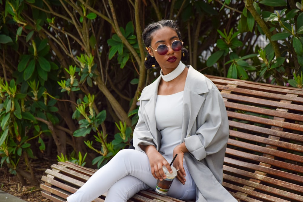 woman in white long sleeve shirt and white pants sitting on brown wooden bench