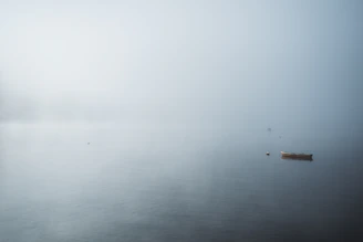 A serene backwater with a small boat, framed by soft morning light and gentle fog.