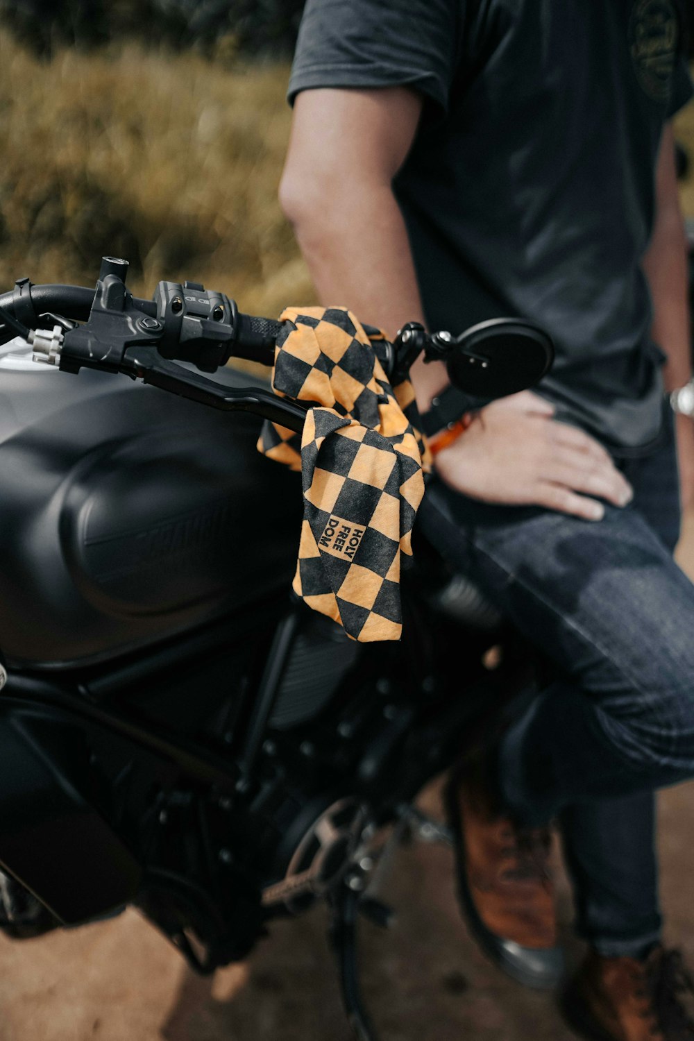 man in black t-shirt and blue denim jeans sitting on black motorcycle