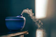 A modern humidifier releasing mist in a softly lit bedroom setting.