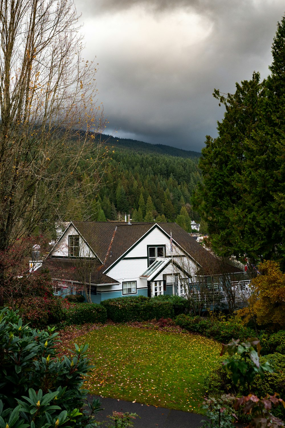 white and black house surrounded by trees under cloudy sky during daytime