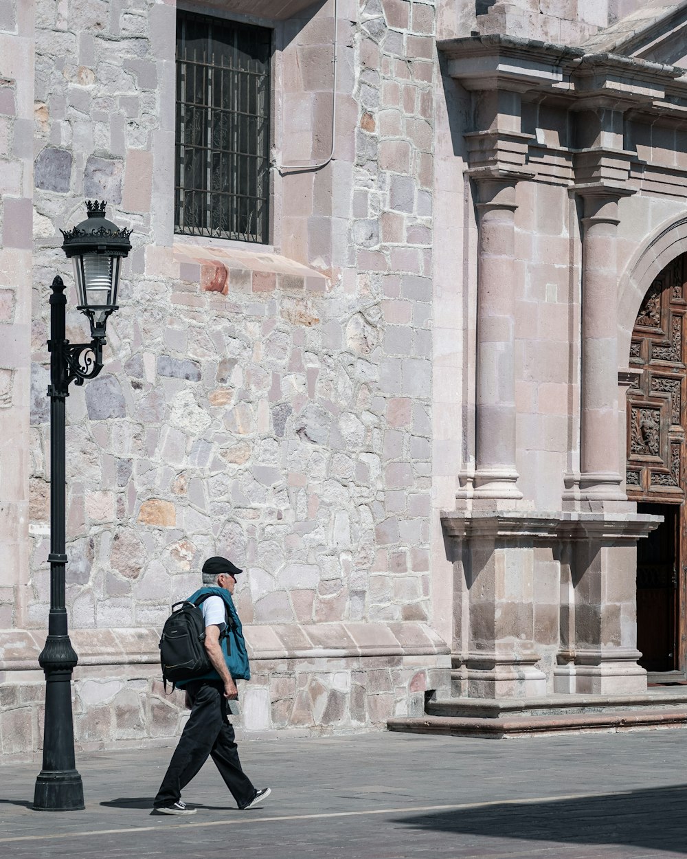 man in blue jacket walking on sidewalk during daytime