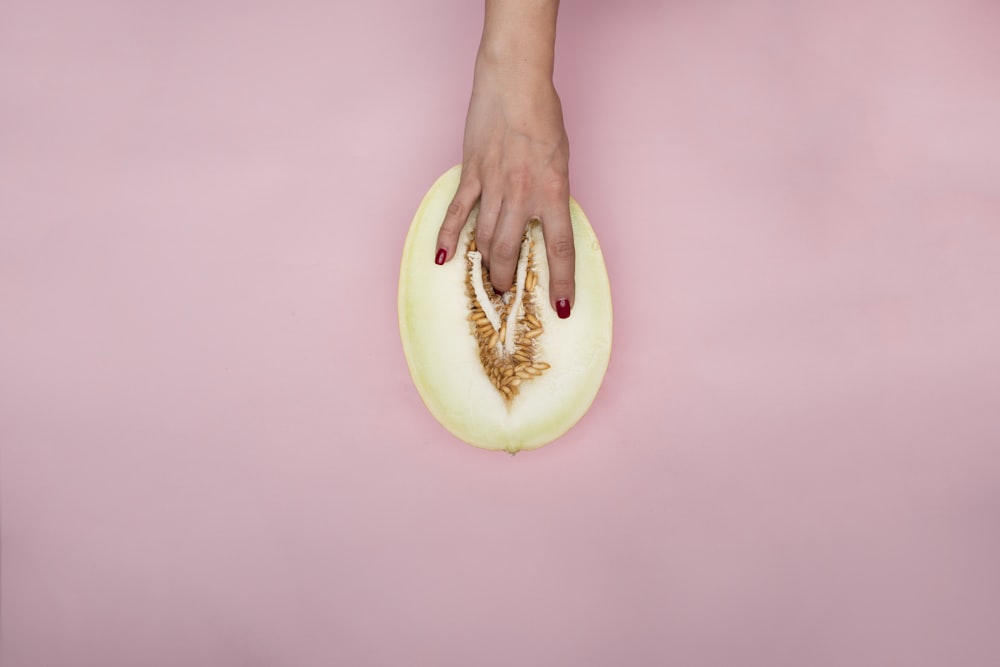 person holding sliced green fruit