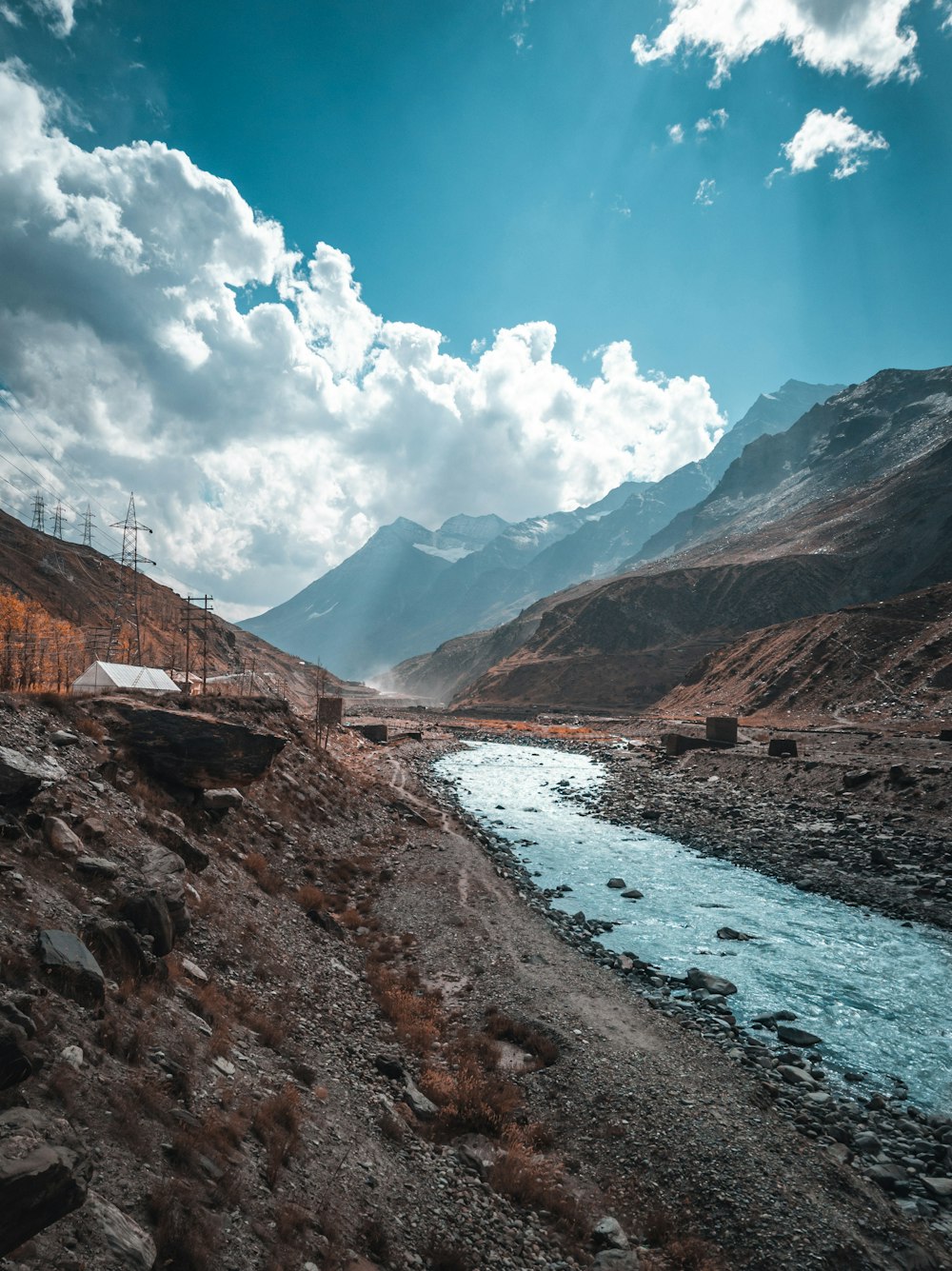 Brauner Rocky Mountain neben dem Fluss tagsüber unter blauem Himmel