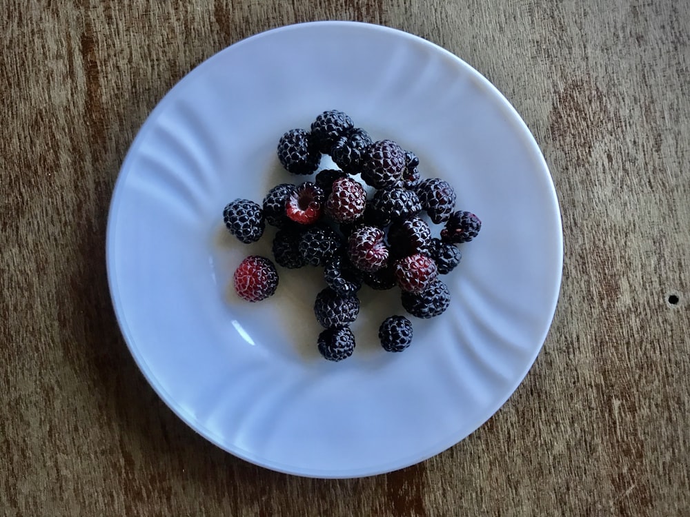 red and black berries on white ceramic plate