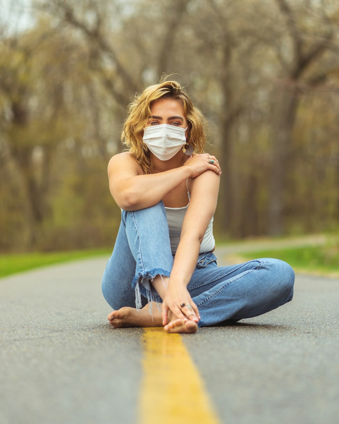 woman in blue denim jeans and white shirt sitting on road during daytime