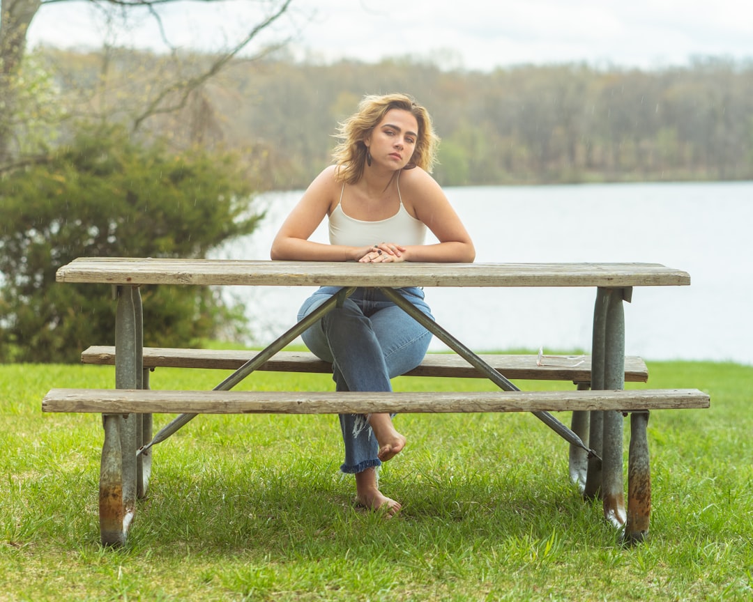 woman in blue denim jeans sitting on brown wooden bench during daytime