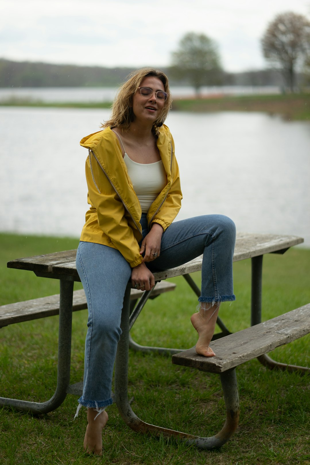 woman in yellow cardigan and blue denim jeans sitting on brown wooden bench