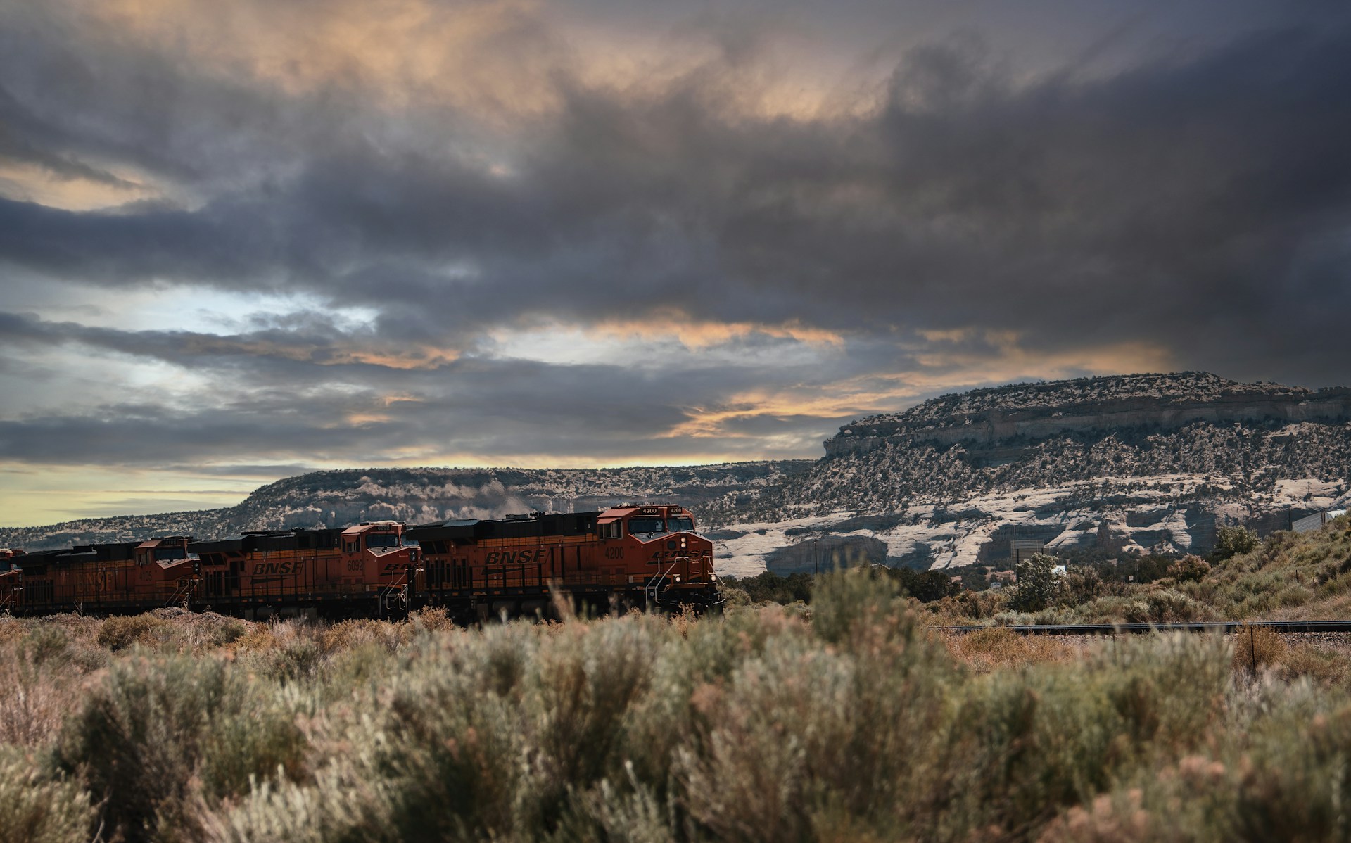 red train on rail road near city under cloudy sky during daytime