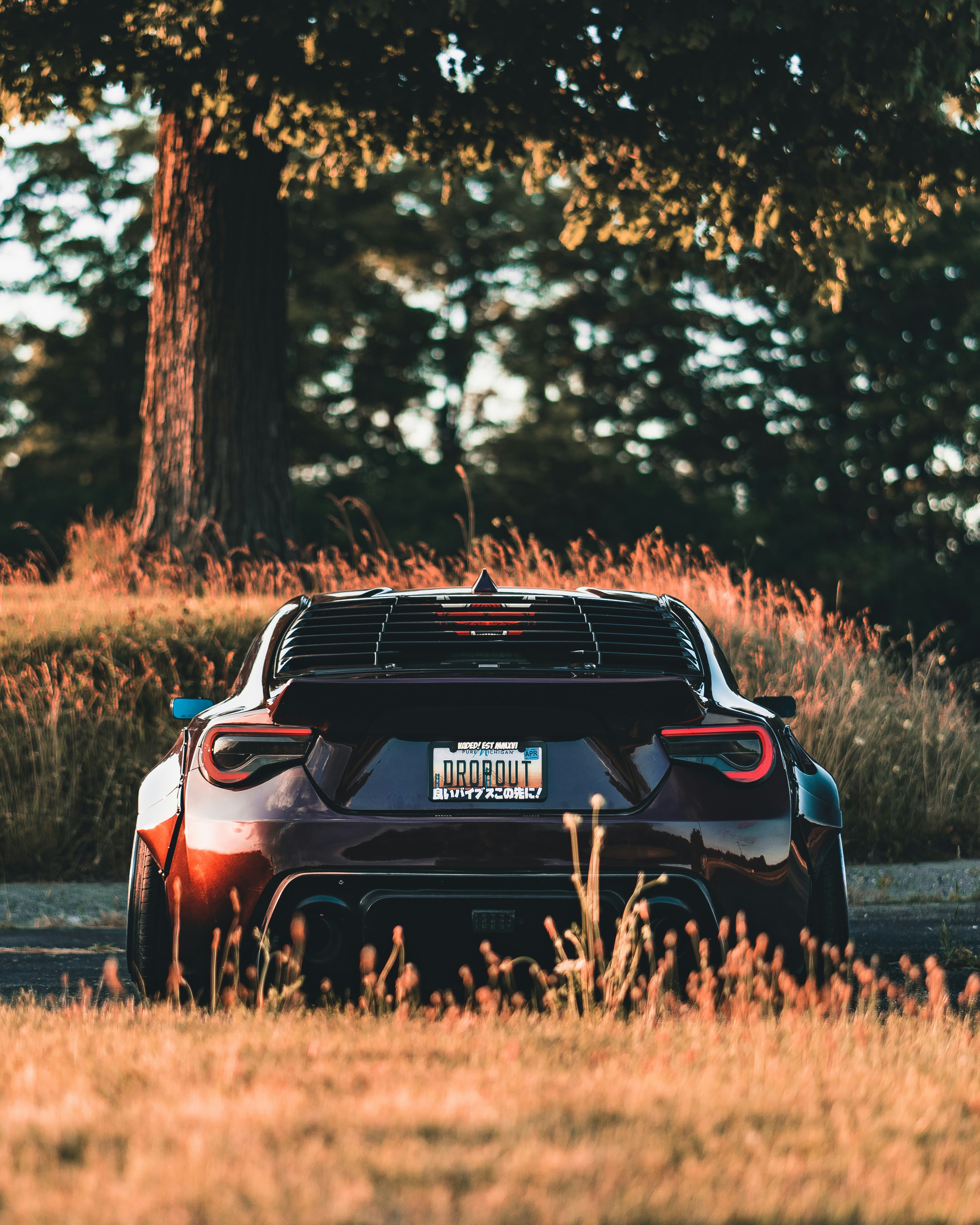 昼間の茶色の芝生のフィールドに赤と黒の車の写真 Unsplashで見つける車の無料写真