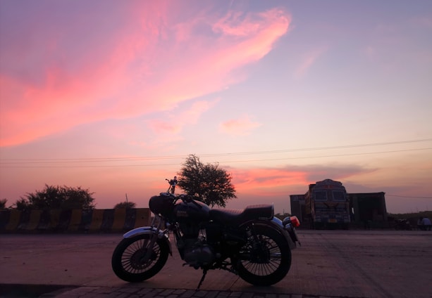 A tow truck parked on a roadside with a sunset in the background.