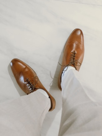brown leather shoes on white textile
