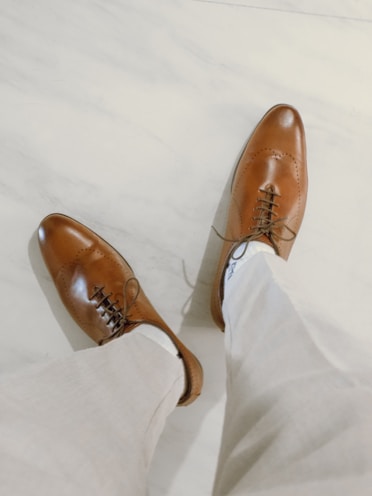 brown leather shoes on white textile