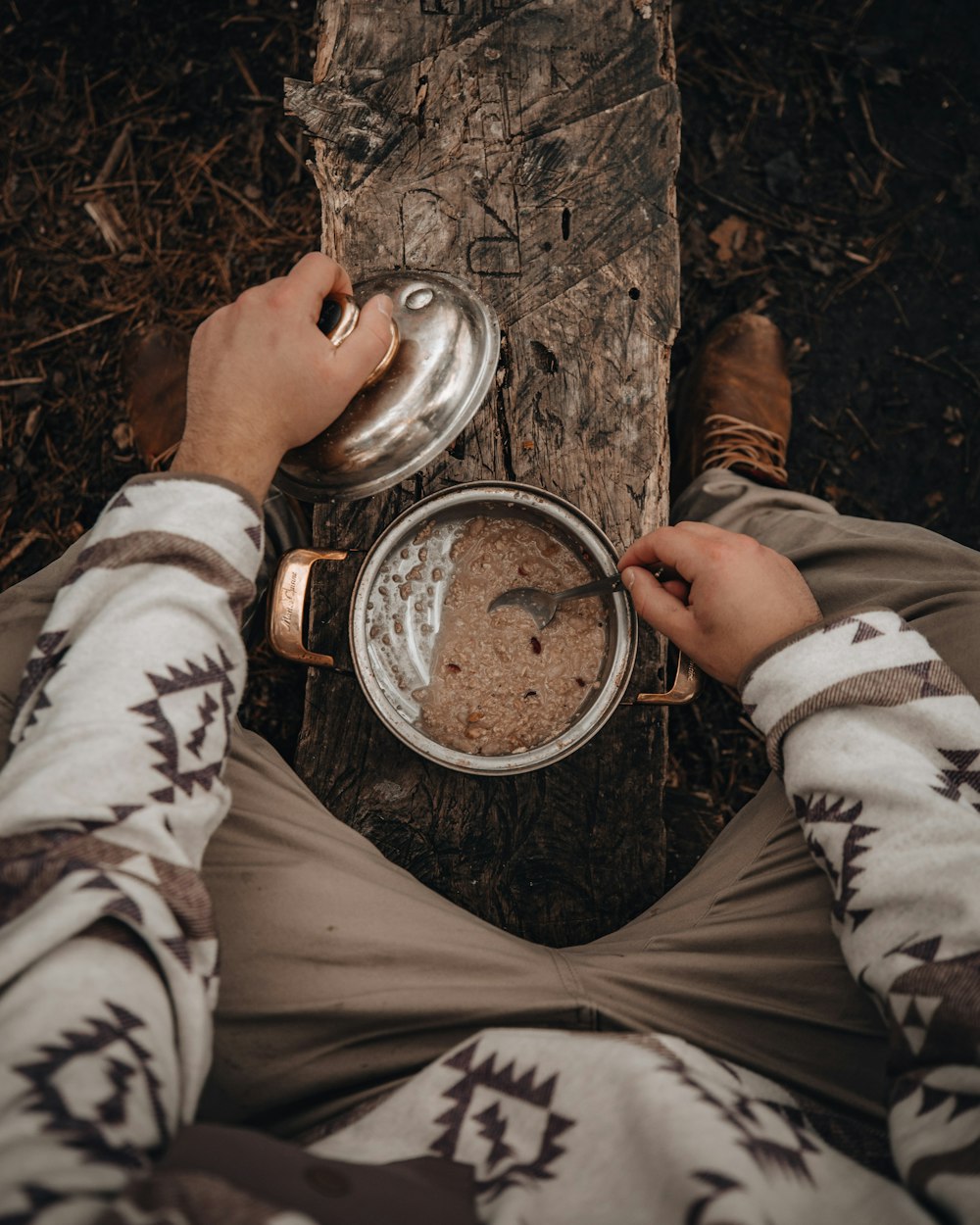 person in white and brown camouflage jacket holding stainless steel round container