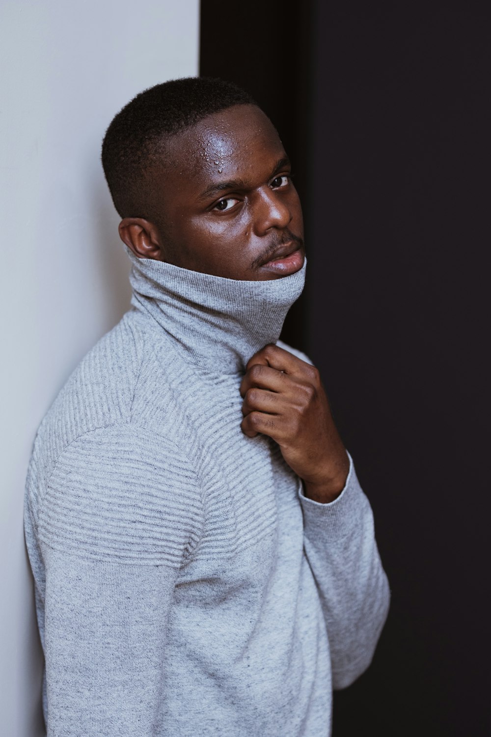 man in gray sweater covering his face with white scarf