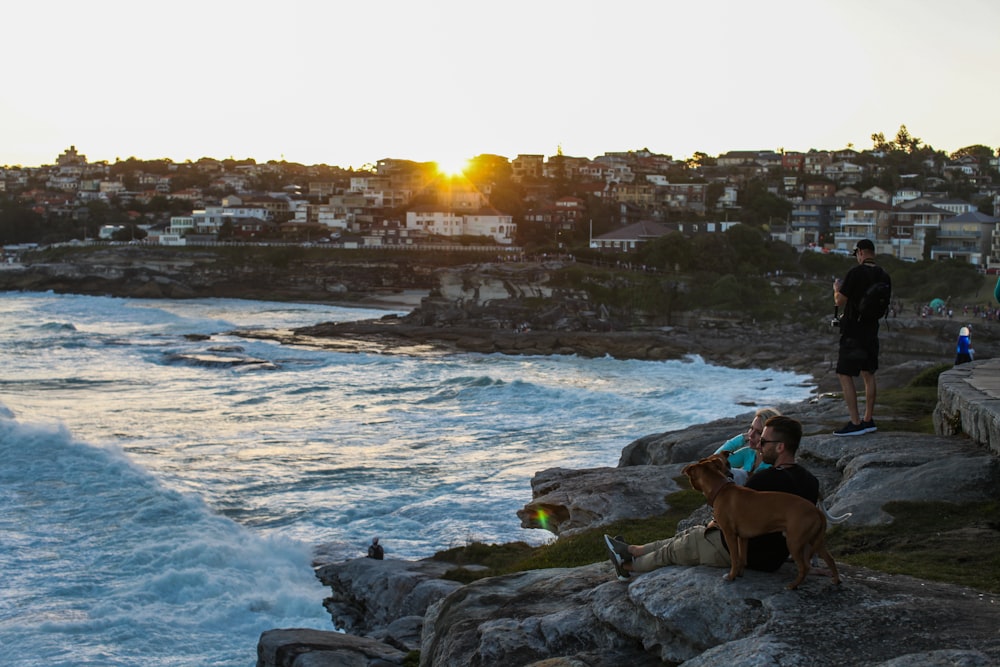 man and woman sitting on rock near body of water during daytime