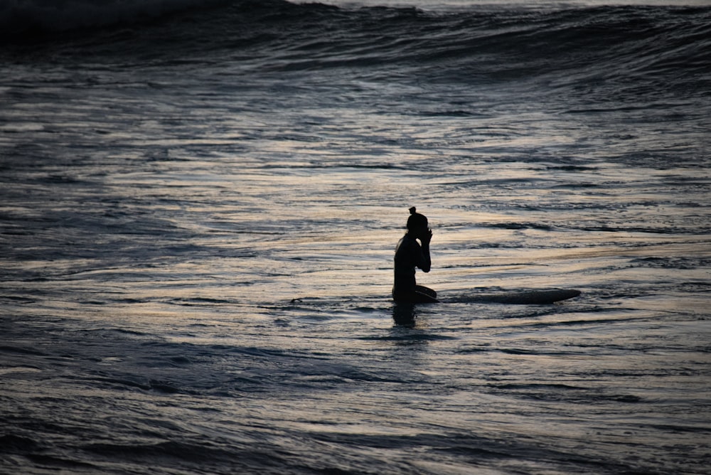 silhouette of woman standing on sea water during daytime