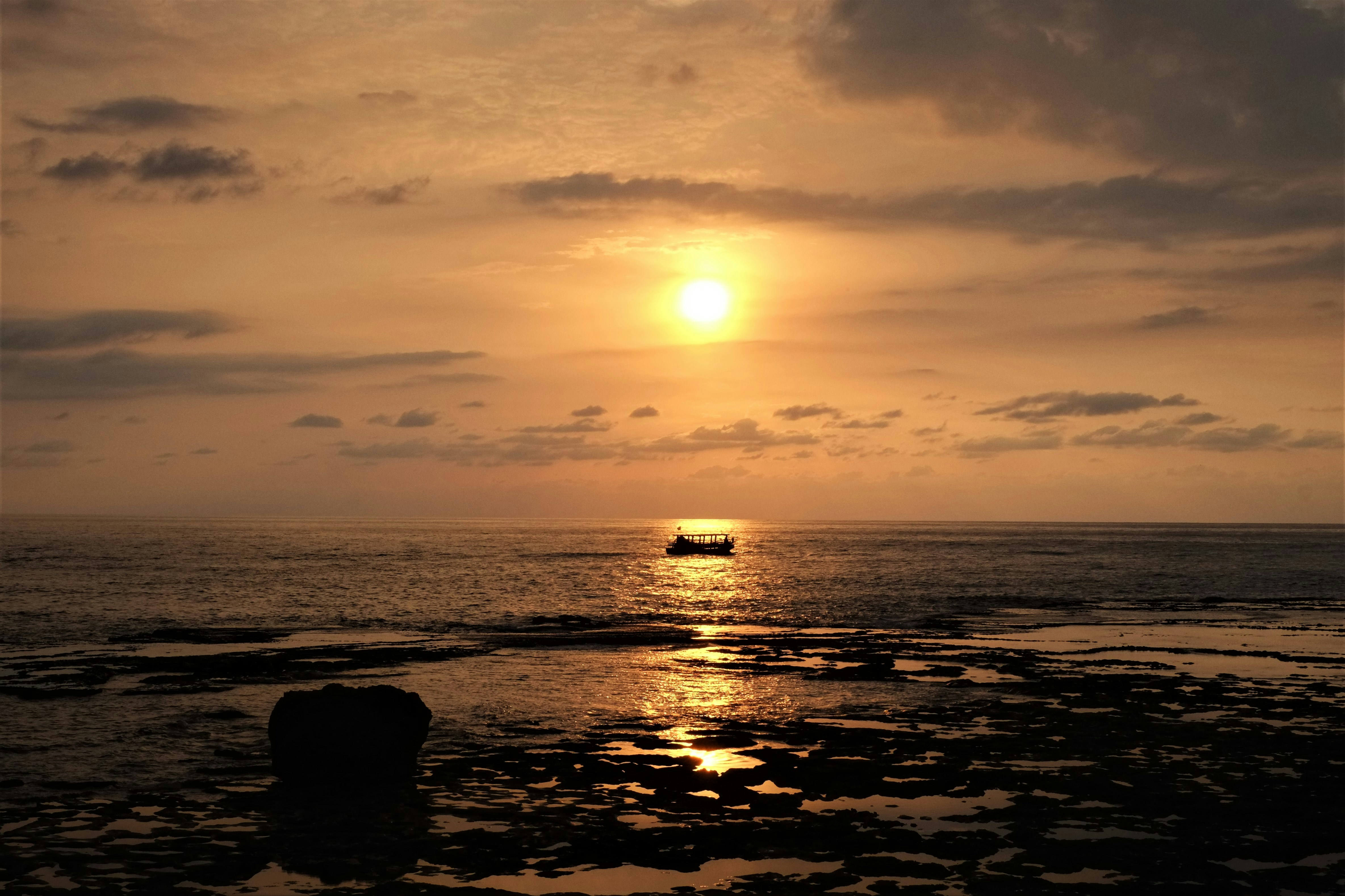 silhouette of rocks on sea during sunset