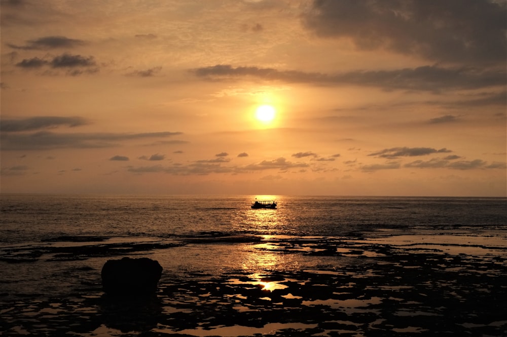 silhouette of rocks on sea during sunset