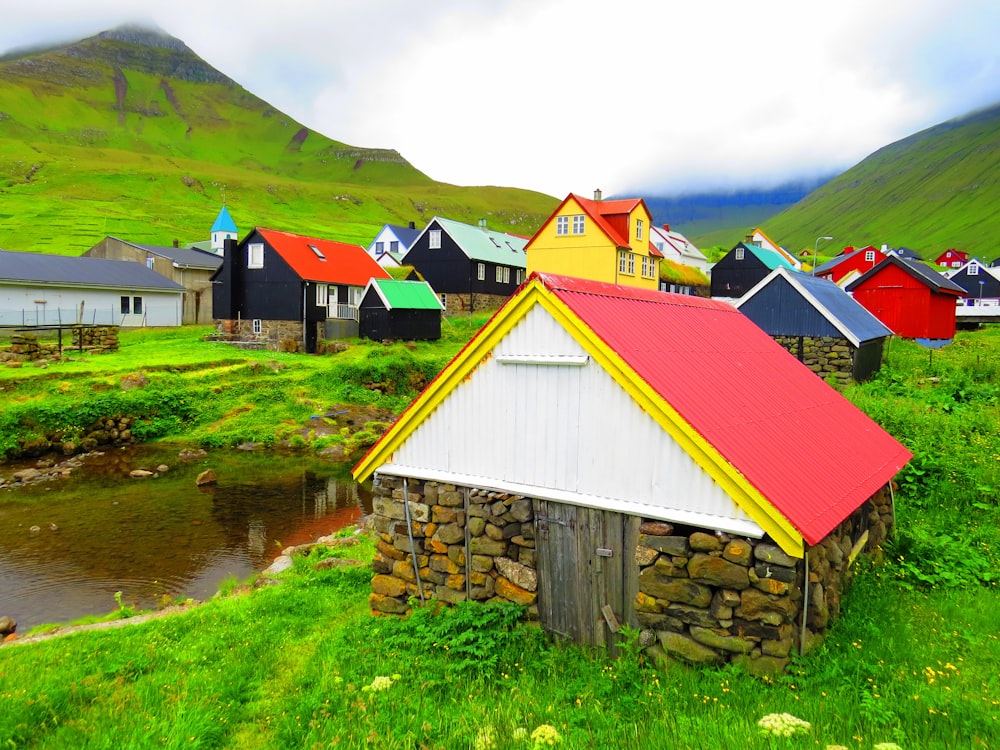 Casa de madera marrón y roja cerca del campo de hierba verde y el lago durante el día