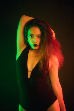 A striking photo of a confident woman in deep crimson lighting, framed by a shadowy city alley.