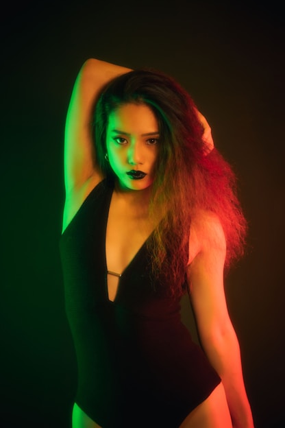 Dramatic portrait of a confident black woman with glowing skin under rim lighting on a black background with gold accents.