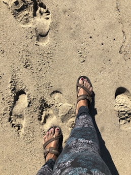 A person wearing sandals walking on a sunny beach.