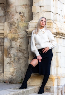 photography poses for women,how to photograph woman in white sweater and black skirt sitting on concrete wall during daytime