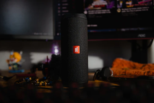 Close-up of a sleek black Village Sounds Bluetooth speaker glowing softly in a cozy living room.