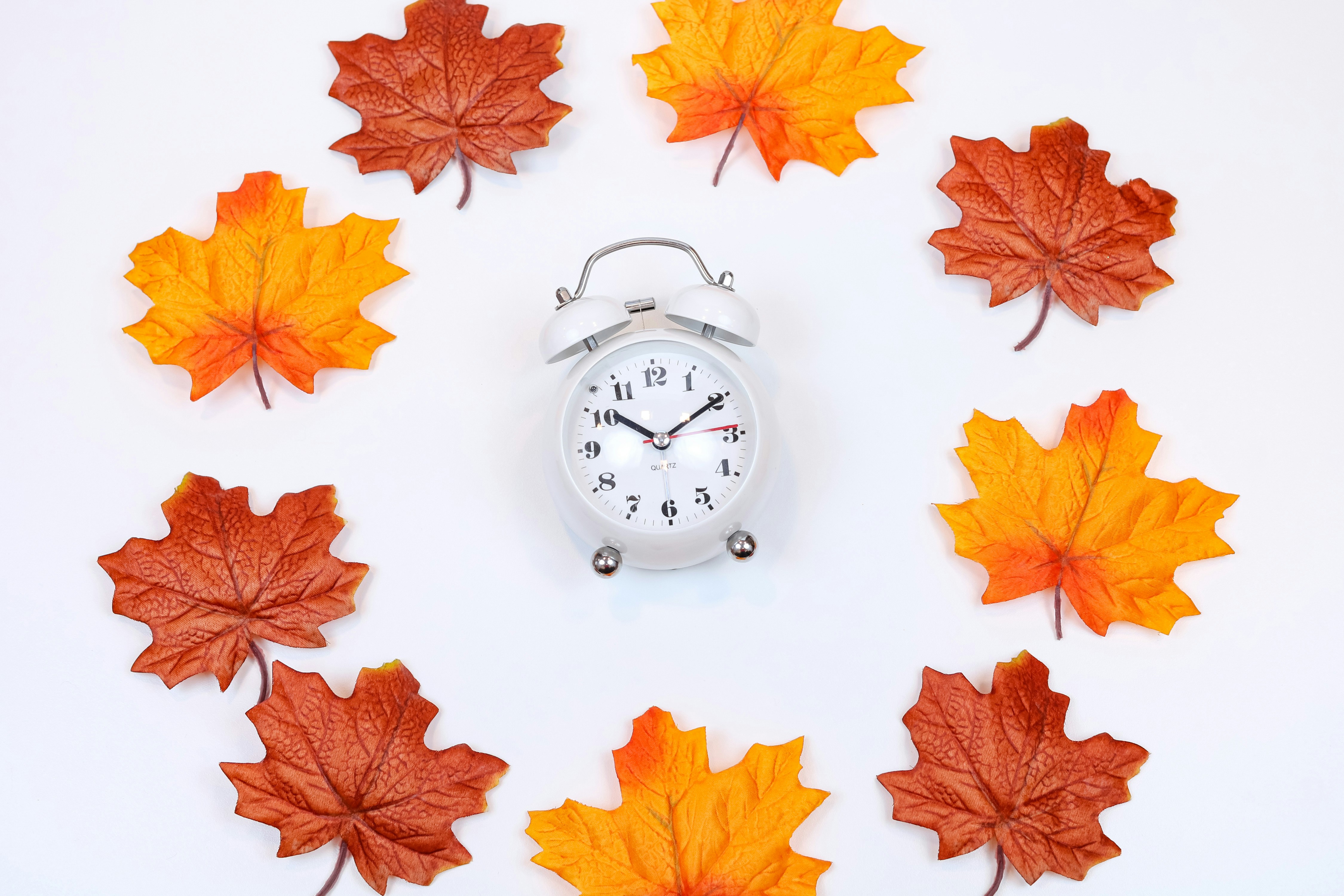 Orange, red, and brown autumn leaves in a beautiful flat lay with a clock for fall. Perfect for Black Friday or Cyber Monday sales and promos.