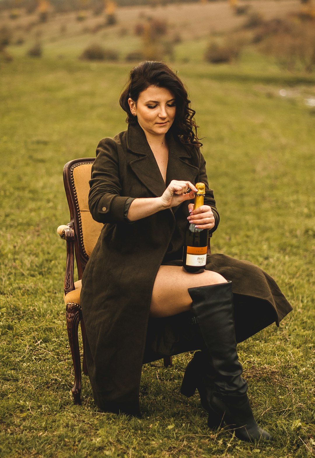 woman in black blazer holding bottle sitting on chair