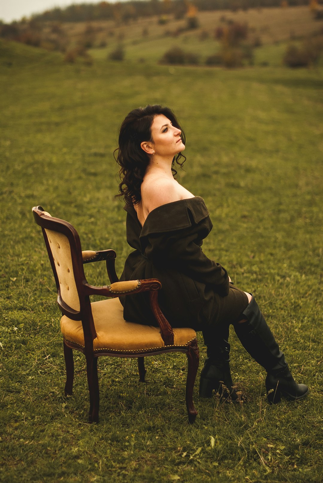 woman in black off shoulder dress sitting on brown wooden armchair