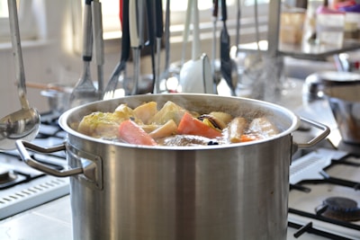 Close-up of a stainless steel stockpot filled with fresh vegetables ready for cooking.