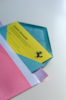 An arrangement of colorful envelopes and a yellow card with printed text and a logo of a rearing horse. The envelopes are in shades of blue, pink, and white, displayed in overlapping layers.