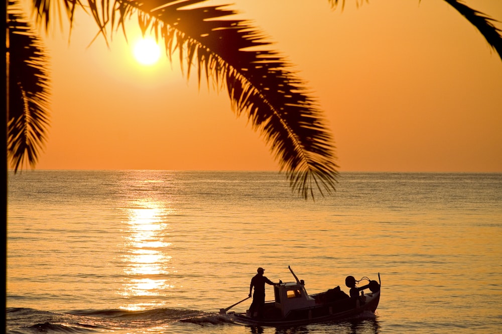 silhouette of 2 people riding on boat during sunset