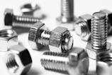 Close-up of galvanized iron bolts and nuts neatly arranged on a workshop table.