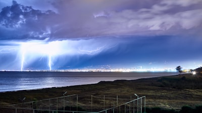 white metal fence near body of water under blue sky and white clouds during daytime