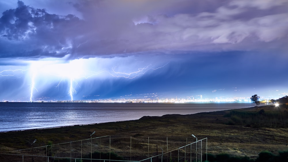 cerca de metal branco perto do corpo de água sob o céu azul e nuvens brancas durante o dia