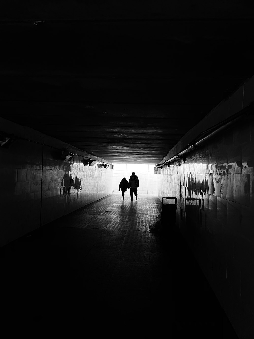 grayscale photo of 2 person walking on hallway