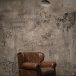 brown wooden armchair beside white wall