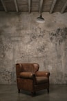 brown wooden armchair beside white wall