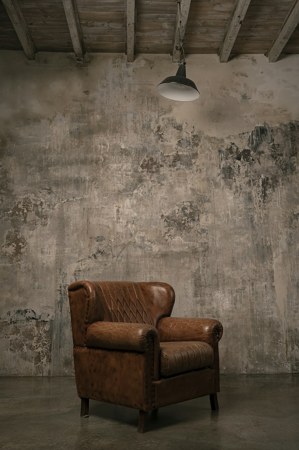 fauteuil en bois marron à côté d’un mur blanc