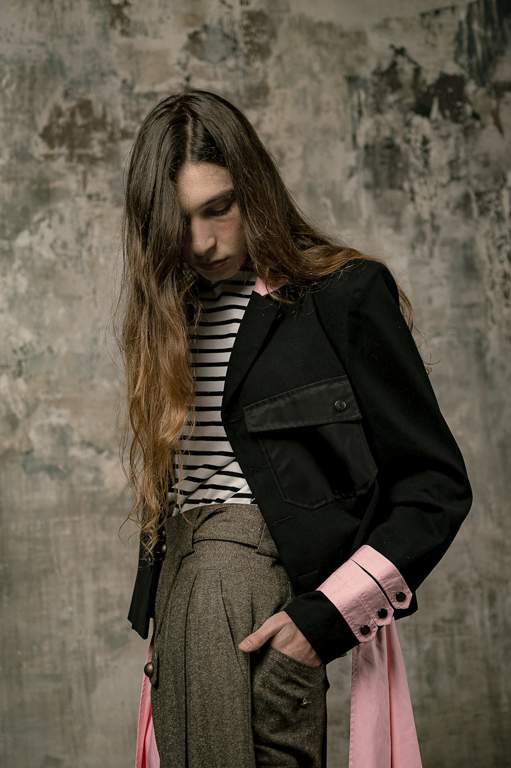 woman in black coat standing near gray wall