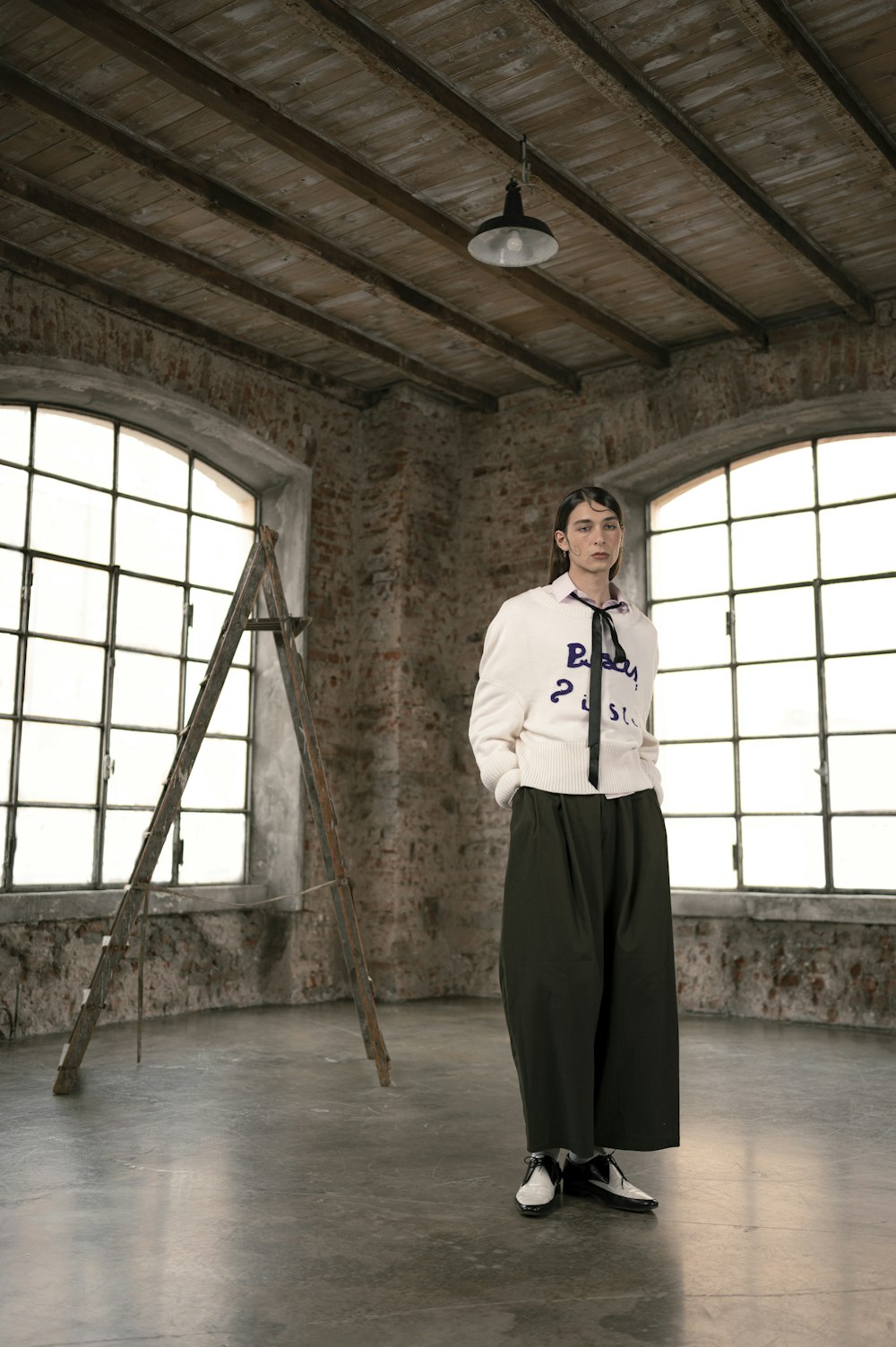 woman in white long sleeve shirt and black pants standing on brown wooden floor