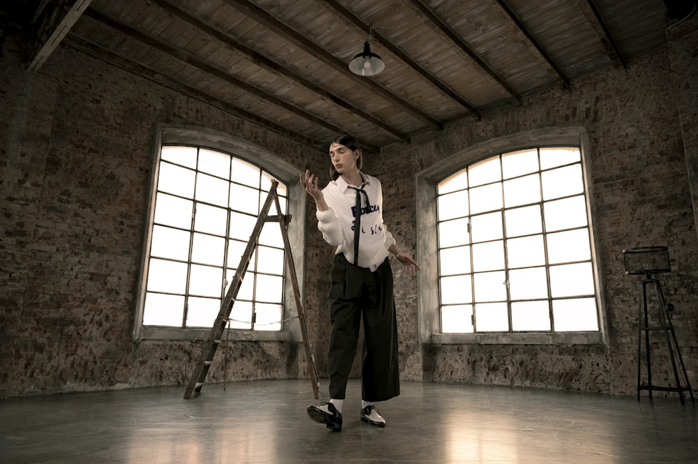 man in white dress shirt and black pants standing on brown wooden floor