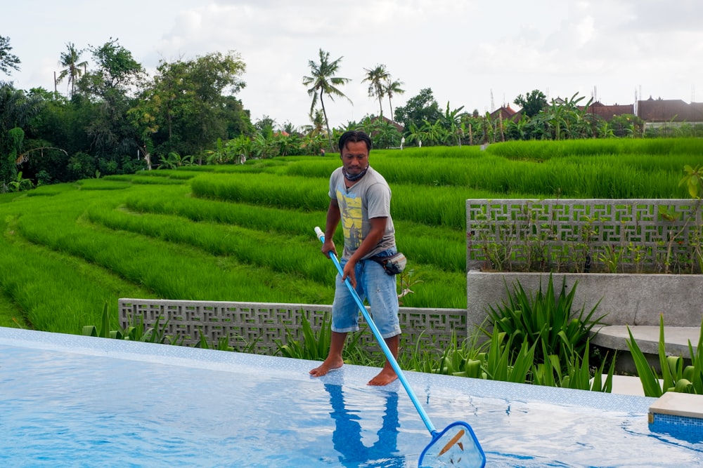 man in white polo shirt and blue denim jeans standing on swimming pool during daytime