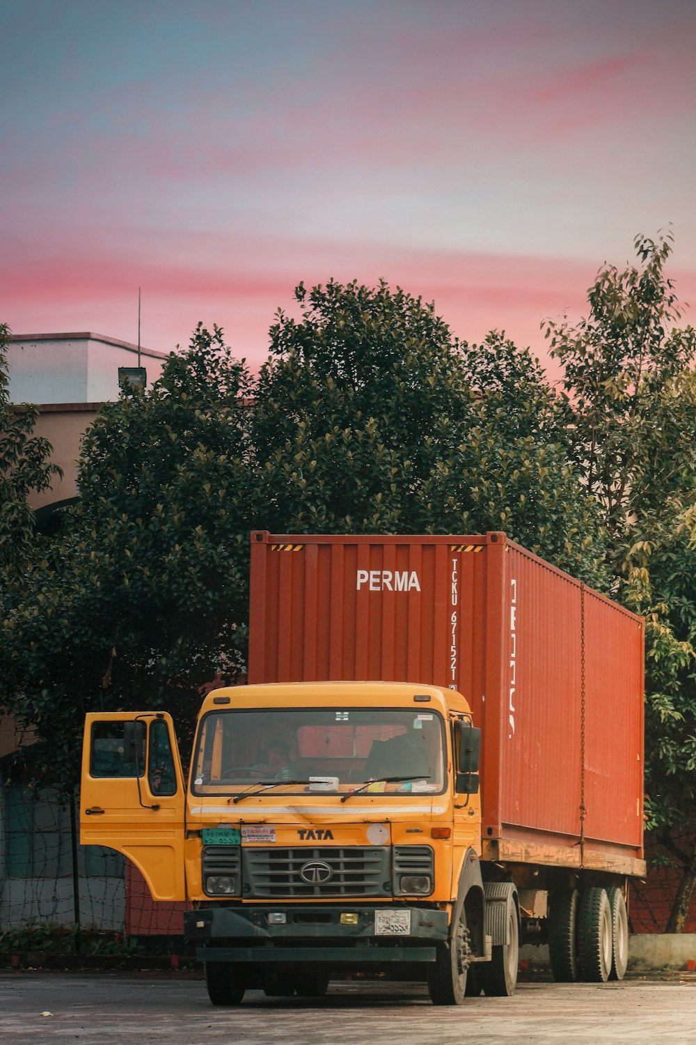 yellow truck parked beside green tree during daytime