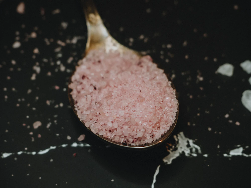 Spoonful of pink bath salt on dark marble