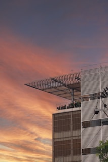 Modern residential building with warm mustard and metallic gray accents at sunset.