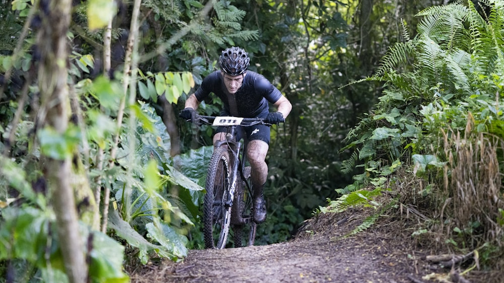 man in black shirt riding bicycle on forest during daytime